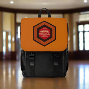 A black and brown backpack with a flap front design and a graphic on the front pocket. It has multiple compartments as indicated by the zippers and straps.